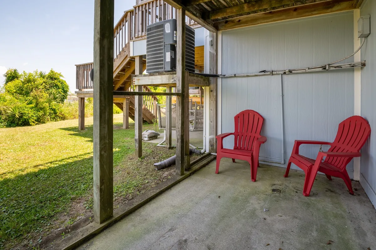 An exterior scene with bright red chairs on a green lawn, adjacent to a staircase. The setting is casual and inviting, oriented for enjoying the outdoors, watching sunsets, or socializing after a day active on the water.