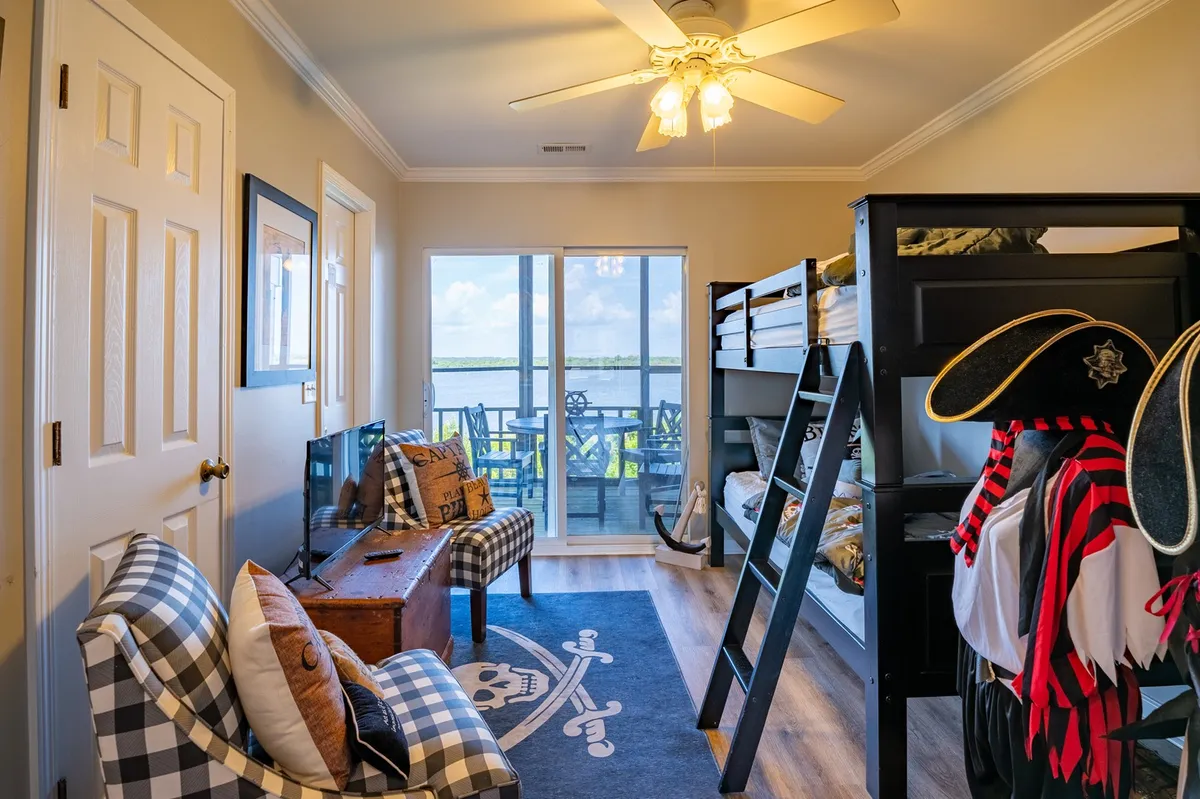 A whimsical bunkroom featuring a pirate-themed bunk bed, playful decor, and a sliding glass door that opens to the patio. The room is bright and fun, filled with elements designed to spark imagination and play.