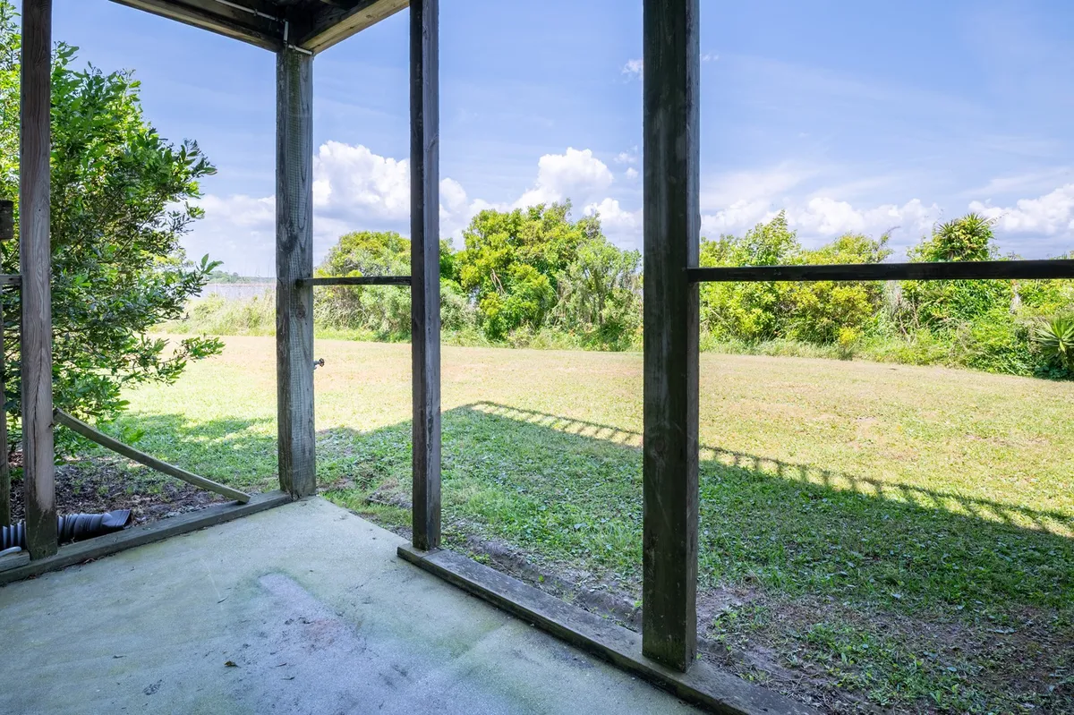 A wide porch framed by sturdy wooden pillars opens onto a lush, green landscape with distant views. The space is inviting for sitting and relaxing, suggesting opportunities for wildlife spotting or enjoying quiet evenings outdoors.