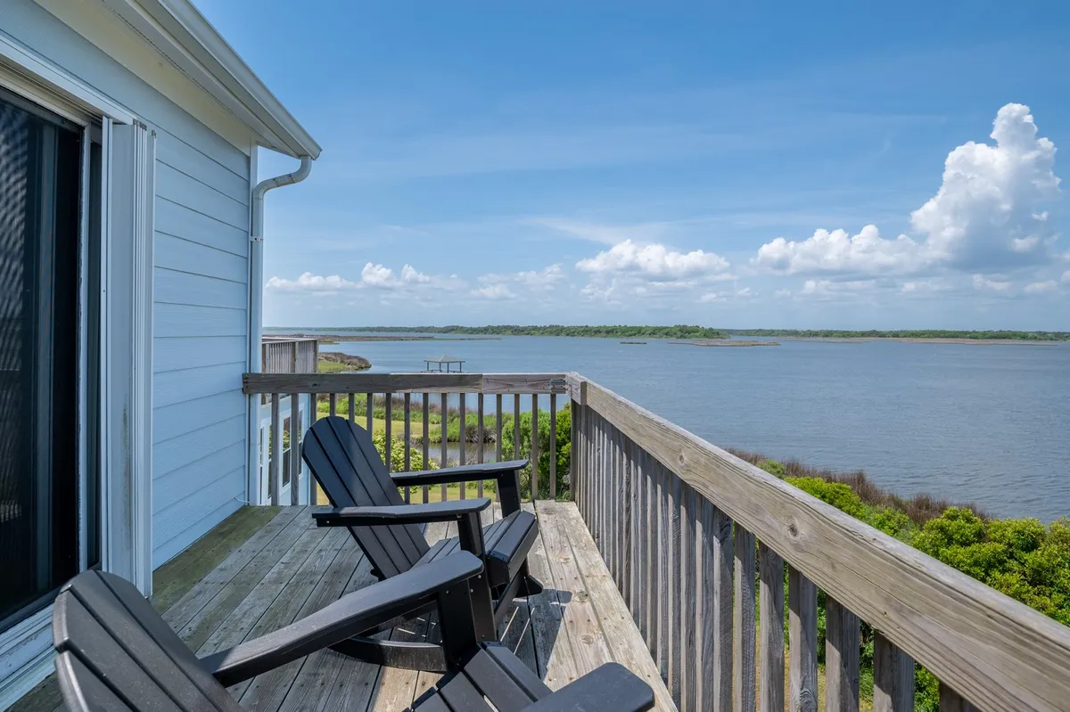 A set of Adirondack chairs overlook calm water and lush greenery, inviting guests to relax, socialize, or watch the sunrise and stars. The mood is tranquil and perfect for evening gatherings or peaceful sunsets.
